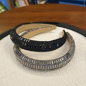 Détail de deux serre-têtes rembourrés avec des strass rectangulaires brillants noirs et argentés