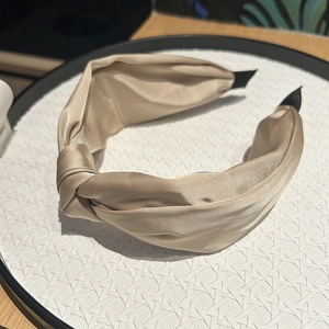 Détail du serre-tête noué en satin champagne avec une texture soyeuse et brillante