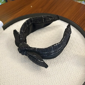 Detail view of black and white tweed headband with knot design on textured display