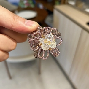 Detail of handmade beaded flower hair claw clip with purple petals and crystal center