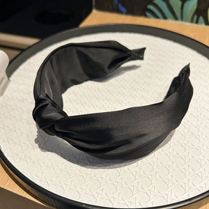 Gros plan d'un serre-tête large en satin noir avec un design noué élégant et chic