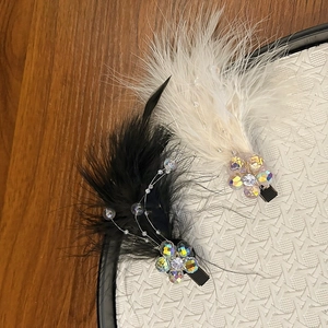 Macro shot of fluffy feather hair clips with iridescent crystal flowers and beaded wire