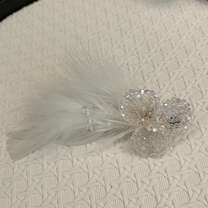 Detailed close-up of white feather hair clip with handcrafted crystal flower beadwork