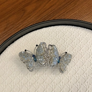 Detail of silver butterfly hair clip with shimmering rhinestones and blue crystal accents