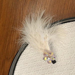Close-up of white feather hair clip with crystal beads and sparkling rhinestone flower