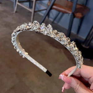 Dettaglio cerchietto scintillante con strass e cristalli chiari su metallo argento