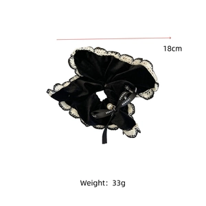 Detail of black velvet scrunchie with beige lace edges and a pearl ribbon bow charm