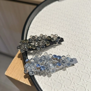 Dettaglio di fermagli per capelli con cristalli sfaccettati blu e grigi su vassoio