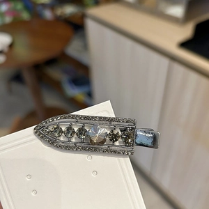 Detailed macro view of a luxury gunmetal hair clip with inlaid grey crystals