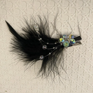Macro detail of black feather hair clip with iridescent beads and silver alligator clip