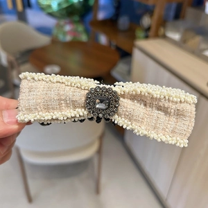 Detail of tweed bow hair clip with pearl edges and a square crystal metal centerpiece