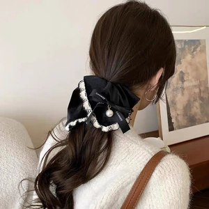 Detailed back view of a black velvet bow hair clip with white lace trim and pearl on hair