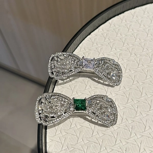 Détail de barrettes nœud argentées avec cristaux étincelants et zircon taille émeraude