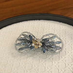 Détail d'une pince à cheveux nœud en cristal tissé avec papillon doré et perles