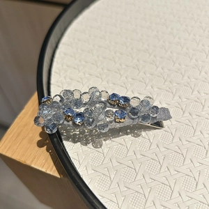 Dettaglio del fermaglio con perle di cristallo blu chiaro e scuro e base in tessuto argento