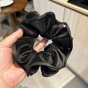 Detailed texture of black velvet hair scrunchie with sparkling gold metallic thread