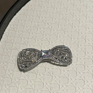 Détail de la pince à cheveux nœud argenté avec strass brillants et pierre carrée centrale