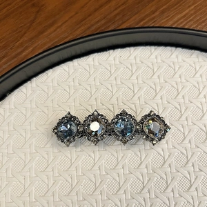 Macro detail of vintage hair clip featuring blue diamond crystals and antique silver plating