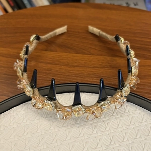 Détail d'un serre-tête avec cristaux champagne et pointes noires sur plateau