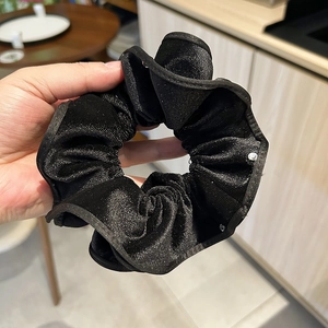 Close-up of black velvet scrunchie with silver glitter texture and lace trim detail