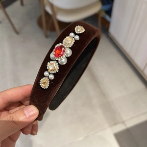 Close-up of red crystal and white pearls on a vintage brown velvet headband hair accessory