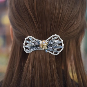 Vue détaillée de la pince à cheveux nœud en cristal tissé main sur cheveux bruns longs