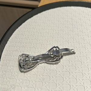Détail d'une barrette à nœud argentée avec strass, motif évidé et fermoir à ressort robuste