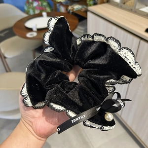 Close-up of velvet hair scrunchie with lace edge, ribbon bow and pearl pendant
