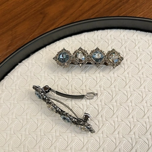 Detail view of vintage hair clip with blue gemstones and metallic spring mechanism