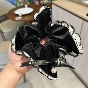 Detail of black velvet scrunchie with white lace trim, pearl pendant and ribbon bow