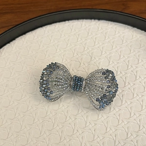 Détail d'une pince à cheveux en cristal avec strass bleus et transparents sur plateau