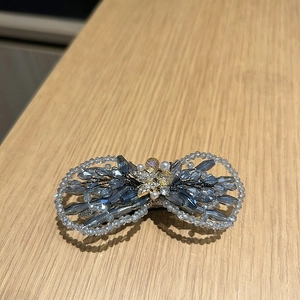 Gros plan détaillé de la barrette nœud en perles de cristal bleu avec abeille dorée
