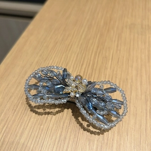 Détail d'une pince à cheveux en perles de cristal bleues et grises avec un papillon doré