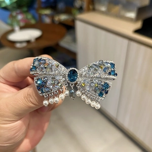Détail de la pince à cheveux nœud en cristal bleu avec pendentifs en perles blanches