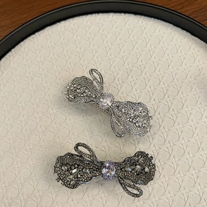 Detail von luxuriösen Strass-Schleifen-Haarspangen in Silber und Gun-Black auf Tablett
