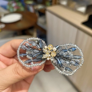 Détail d'une pince à cheveux en cristal avec perles bleues et papillon doré