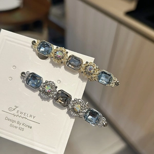 Close-up of vintage gold hair clips with sea blue gems and floral ornaments on card