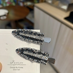 Close-up of sparkling grey and clear crystal rhinestones on a silver duckbill hair clip