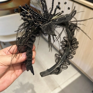 Detail of black lace headband featuring elegant feathers, sequins and handcrafted pearls