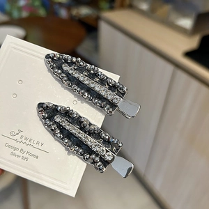 Detailed macro of two handcrafted hair clips with grey beads and sparkling rhinestones