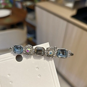 Detail of vintage silver hair clip with blue and grey crystals on white card