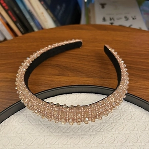 Detailed view of champagne crystal headband with high-density inlay on a woven tray