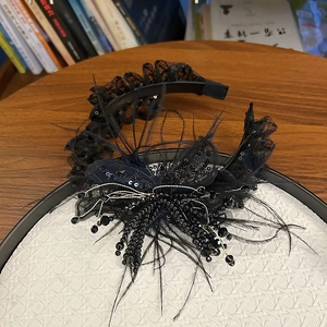 Detailed macro of a black lace headband featuring elegant feathers, beads, and sequins