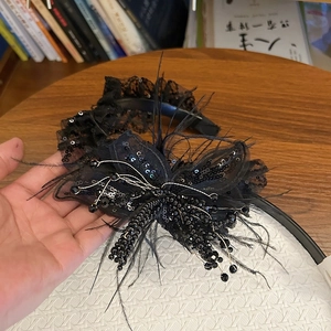 Detail of black lace flower headband with sequins, beads, and elegant feathers decoration