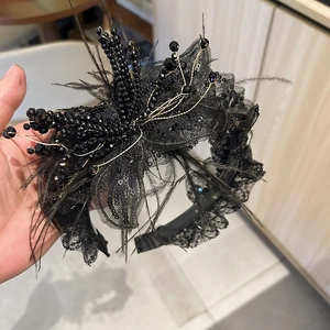 Detail of luxury black lace headband with pearls, feathers, and shimmering sequins