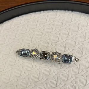 Detail of vintage silver hair clip with blue rectangle crystals and floral openwork