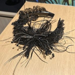 Detail of gothic lace headband with black feathers and dangling pearls on wood