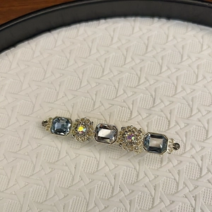 Macro shot of vintage gold-plated hair clip with blue crystals and floral rhinestone details