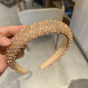 Détail d'un serre-tête rembourré doré champagne orné de cristaux étincelants denses