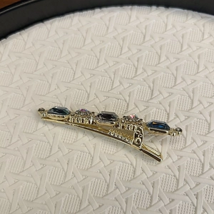 Detail of luxury duckbill hair clip with blue rectangle gems and colorful rhinestones